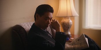Movie still from “Tokyo Vice” (2022), created by J.T. Rogers – A man sitting on a couch in front of a lamp; Medium shot, Low angle