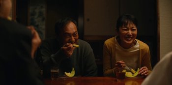 Movie still from “Tokyo Vice” (2022), created by J.T. Rogers – A man and a woman sitting at a wooden table; Medium shot, Over the shoulder angle
