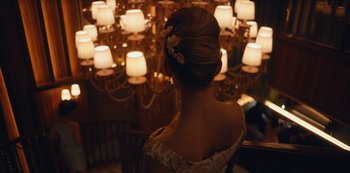 Movie still from “Tokyo Vice” (2022), created by J.T. Rogers – A woman in a white dress is looking at a chandelier; Medium shot, Over the shoulder angle