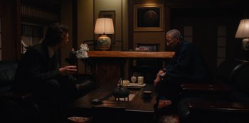 Movie still from “Tokyo Vice” (2022), created by J.T. Rogers – Two people sitting at a table in a living room; Medium shot, Over the shoulder angle