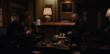 Movie still from “Tokyo Vice” (2022), created by J.T. Rogers – Two men sitting at a wooden table in a room; Medium shot, Over the shoulder angle