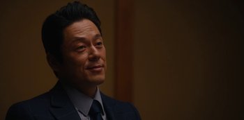 Movie still from “Tokyo Vice” (2022), created by J.T. Rogers – A person wearing a suit and tie; Close Up shot, Over the shoulder angle