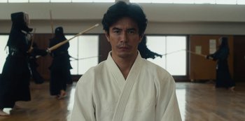 Movie still from “Tokyo Vice” (2022), created by J.T. Rogers – A man in a white robe stands in a room; Medium shot, Low angle