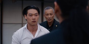 Movie still from “Tokyo Vice” (2022), created by J.T. Rogers – A group of men standing next to each other in a room; Close Up shot, Over the shoulder angle