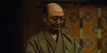 Movie still from “Tokyo Vice” (2022), created by J.T. Rogers – An older man wearing a green robe and glasses; Close Up shot, Low angle