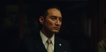 Movie still from “Tokyo Vice” (2022), created by J.T. Rogers – A person wearing a suit and tie; Close Up shot, Low angle