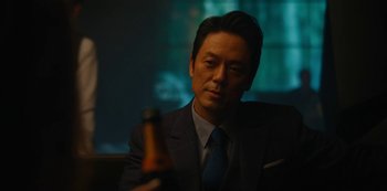 Movie still from “Tokyo Vice” (2022), created by J.T. Rogers – A man in a suit holding a bottle of beer; Close Up shot, Over the shoulder angle