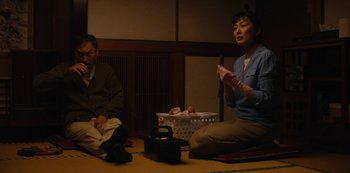 Movie still from “Tokyo Vice” (2022), created by J.T. Rogers – Two people sitting on the ground in front of a basket; Medium shot, High angle