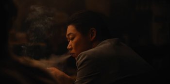 Movie still from “Tokyo Vice” (2022), created by J.T. Rogers – A man sitting in front of a wall smoking a cigarette; Close Up shot, Low angle