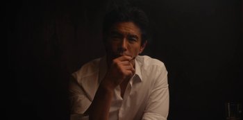 Movie still from “Tokyo Vice” (2022), created by J.T. Rogers – A man in a white dress shirt is holding his hand to his chin; Close Up shot, Low angle