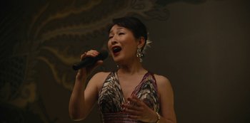 Movie still from “Tokyo Vice” (2022), created by J.T. Rogers – A woman is singing into a microphone; Medium shot, High angle