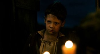 Movie still from “Tom Thumb” (2001), directed by Olivier Dahan – A young boy standing in front of two candles in the dark; Close Up shot, Low angle