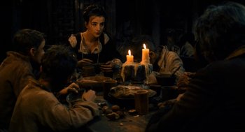 Movie still from “Tom Thumb” (2001), directed by Olivier Dahan – A group of people sitting around a table with candles; Medium shot, High angle