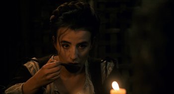 Movie still from “Tom Thumb” (2001), directed by Olivier Dahan – A young woman is lighting a candle in the dark; Close Up shot, High angle