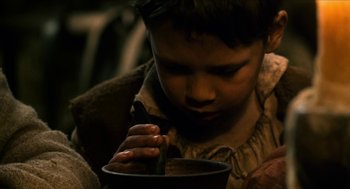 Movie still from “Tom Thumb” (2001), directed by Olivier Dahan – A young boy is holding a spoon in a bowl; Close Up shot, High angle