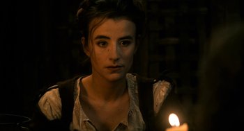 Movie still from “Tom Thumb” (2001), directed by Olivier Dahan – A young woman is standing in front of a lit candle; Close Up shot, High angle