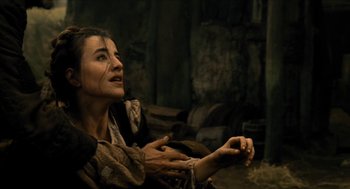 Movie still from “Tom Thumb” (2001), directed by Olivier Dahan – A woman sitting on the ground with her hands in the air; Medium shot, High angle