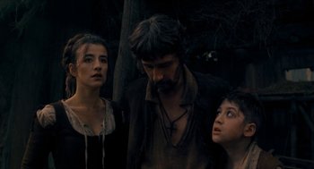 Movie still from “Tom Thumb” (2001), directed by Olivier Dahan – A man and two women standing next to each other; Medium shot, Over the shoulder angle