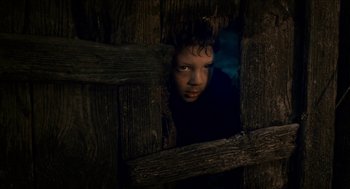 Movie still from “Tom Thumb” (2001), directed by Olivier Dahan – A young boy peeks out from behind a wooden fence; Close Up shot, Low angle