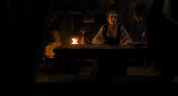 Movie still from “Tom Thumb” (2001), directed by Olivier Dahan – A woman sitting at a table in front of a fireplace; Medium shot, High angle
