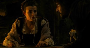 Movie still from “Tom Thumb” (2001), directed by Olivier Dahan – A woman sitting at a table with a man in the background; Medium shot, Over the shoulder angle