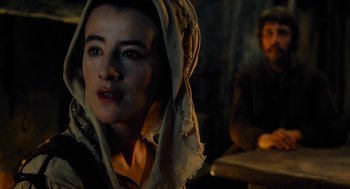 Movie still from “Tom Thumb” (2001), directed by Olivier Dahan – A woman with a hood over her head and a man in the background; Close Up shot, Over the shoulder angle