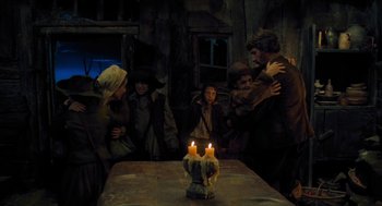 Movie still from “Tom Thumb” (2001), directed by Olivier Dahan – A group of people standing around a table with candles; Medium shot, Over the shoulder angle