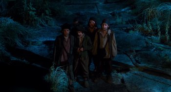 Movie still from “Tom Thumb” (2001), directed by Olivier Dahan – A group of people standing next to each other in the dark; Wide shot, High angle