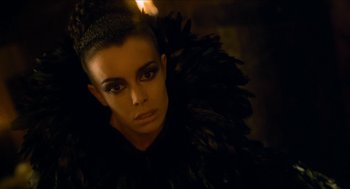 Movie still from “Tom Thumb” (2001), directed by Olivier Dahan – A woman in a black outfit with feathers on her body; Close Up shot, High angle