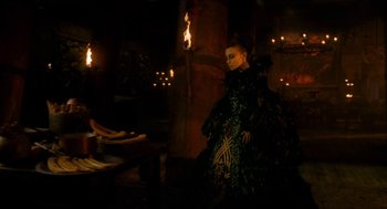 Movie still from “Tom Thumb” (2001), directed by Olivier Dahan – A woman dressed in a costume in a dark room; Wide shot, Over the shoulder angle