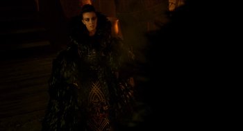 Movie still from “Tom Thumb” (2001), directed by Olivier Dahan – A woman in a black and green dress and feathers; Medium shot, Low angle