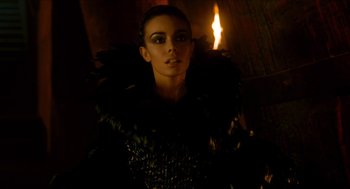 Movie still from “Tom Thumb” (2001), directed by Olivier Dahan – A woman in a black dress with a black feathered outfit; Close Up shot, Low angle