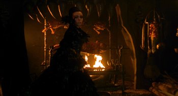 Movie still from “Tom Thumb” (2001), directed by Olivier Dahan – A woman dressed as a witch standing in front of a fire; Medium shot, Over the shoulder angle