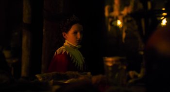 Movie still from “Tom Thumb” (2001), directed by Olivier Dahan – A woman in a red and white dress standing in front of a candle; Close Up shot, Over the shoulder angle