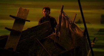 Movie still from “Tom Thumb” (2001), directed by Olivier Dahan – A man standing on top of a pile of wood; Wide shot, Low angle