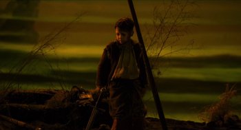 Movie still from “Tom Thumb” (2001), directed by Olivier Dahan – A young boy holding a stick in his hand; Wide shot, High angle
