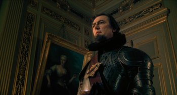 Movie still from “Tom Thumb” (2001), directed by Olivier Dahan – A man dressed as a medieval knight standing in front of a painting; Medium shot, Low angle