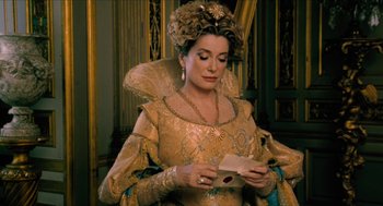 Movie still from “Tom Thumb” (2001), directed by Olivier Dahan – A woman in a gold dress holding an open envelope; Medium shot, High angle