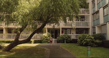 Movie still from “Tomboy” (2011), directed by Céline Sciamma – A person walking down a path in front of an apartment building; Extreme Wide shot, Low angle