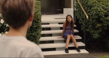Movie still from “Tomboy” (2011), directed by Céline Sciamma – A young girl sitting on the steps of a building; Wide shot, High angle