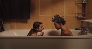 Movie still from “Tomboy” (2011), directed by Céline Sciamma – Two young children in a bath tub one of them is brushing her teeth; Medium shot, High angle