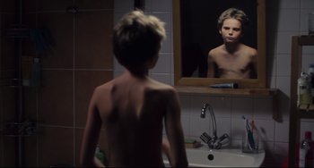 Movie still from “Tomboy” (2011), directed by Céline Sciamma – A young boy looking at himself in the mirror; Medium shot, Over the shoulder angle