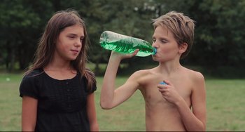 Movie still from “Tomboy” (2011), directed by Céline Sciamma – A boy and a girl drinking water from a green bottle; Medium shot, High angle