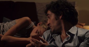 Movie still from “Tomboy” (2011), directed by Céline Sciamma – A man and a boy laying on a couch looking at a phone; Close Up shot, Over the shoulder angle