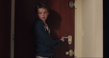 Movie still from “Tomboy” (2011), directed by Céline Sciamma – A young boy holding on to the handle of a door knob; Medium shot, Over the shoulder angle