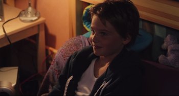 Movie still from “Tomboy” (2011), directed by Céline Sciamma – A young boy sitting in a chair in a room; Close Up shot, Over the shoulder angle