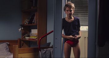 Movie still from “Tomboy” (2011), directed by Céline Sciamma – A young boy standing next to a bookshelf; Medium shot, Low angle