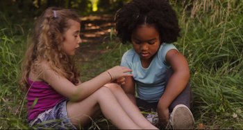 Movie still from “Tomboy” (2011), directed by Céline Sciamma – Two young girls sitting on the ground in the grass; Medium shot, High angle