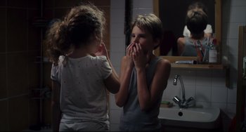 Movie still from “Tomboy” (2011), directed by Céline Sciamma – Two young children in a bathroom one of them is covering his mouth; Close Up shot, Over the shoulder angle