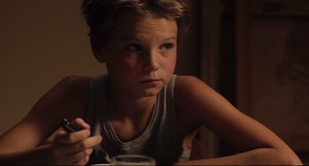 Movie still from “Tomboy” (2011), directed by Céline Sciamma – A young boy sitting at a table with a glass of water; Close Up shot, Over the shoulder angle